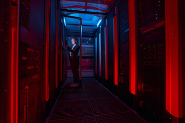 Female technician working on phone with servers in data center