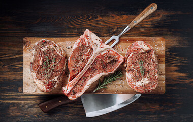 Wall Mural - three lovely raw marbled black Angus beef steaks flavored with a mixture of ground pepper and ready to cook and serve on a dark wooden background.