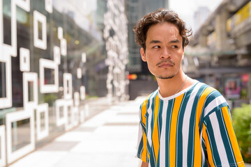 Wall Mural - Portrait of handsome multi-ethnic young man wearing colorful shirt outdoors during summer in city