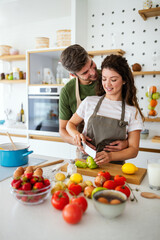 Wall Mural - Happy young couple have fun in kitchen while preparing healthy organic food