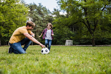 Family Playing With Soccer Ball On Grass