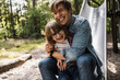 © Westend61 - Father hugging son while sitting on slide in forest