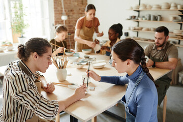 Wall Mural - High angle shot of diverse group of people decorating ceramics in pottery workshop, copy space