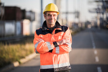 Smiling Male Dock Worker With Arms Crossed On Street At Industry
