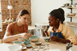 © Seventyfour - Warm toned portrait of two young women enjoying pottery workshop in cozy studio, copy space