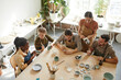 © Seventyfour - High angle shot of creative group of people decorating ceramics in pottery workshop, copy space