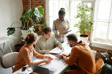 High angle portrait of creative team using laptop while discussing design project in studio, copy space