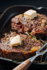 Wall Mural - cooking sumptuous steaks in a grill pan with butter spreading over the steak seasoned with ground pepper and salt with rosemary sprigs