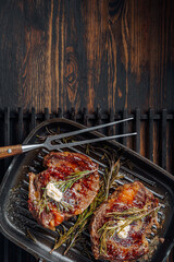 Wall Mural - cooking sumptuous steaks in a grill pan with butter spreading over the steak seasoned with ground pepper and salt with rosemary sprigs