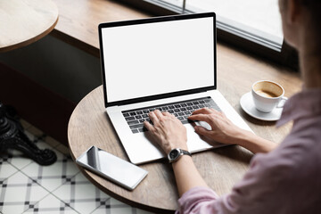 Young woman using laptop computer with blank white screen at cafe. Business woman working in modern office. Freelance lifestyle, e-learning, studying, web site, technology and online shopping concept