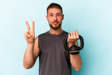 Young caucasian man holding ketlebell isolated on blue background showing number two with fingers.