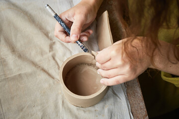 Female ceramist working in pottery studio. Ceramist's Hands Dirty Of Clay. Process of creating pottery. Master ceramist works in her studio