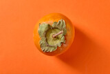 Sweet ripe persimmon on orange background, top view