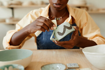 Wall Mural - Close up of unrecognizable African-American woman decorating ceramics in pottery workshop, copy space