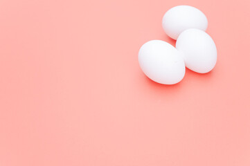 Poster - isolated white eggs on a white and salmon pink background with text space