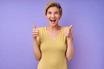 Excited happy beautiful succeed worker concept. Joyful young woman screaming. female keeps hands raised arm, showing thumbs up, while standing over isolated purple background with copy space.