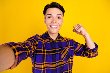 Sticker - Photo of lovely brunet millennial guy show biceps do selfie wear checkered shirt isolated on yellow color background