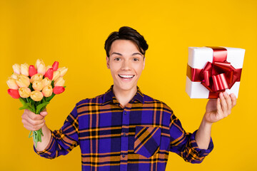 Poster - Photo of millennial funky guy hold flowers present wear checkered shirt isolated on yellow color background