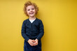 Portrait of adorable child boy in casual wear posing at camera isolated over bright yellow vivid background in studio, kid boy has shy smile, happy, being in good mood. childhood, lifestyle cocnept