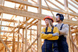 team of constructor engineers in New wooden residential construction home framing. Construction site. Beautiful caucasian lady and man in workwear, hardhat and headset looking at side, at sunny day
