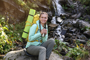 Sticker - Tourist with vacuum flask near waterfall in mountains