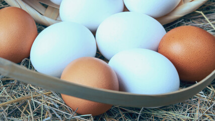 Poster - a lot of fresh chicken eggs in a straw basket on a background of hay. Healthy eating concept