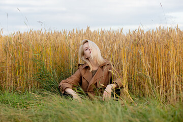 Sticker - Blonde woman in cloak is sitting near wheat field