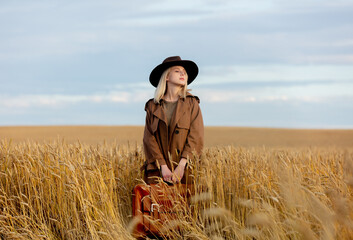 Sticker - Blonde woman in cloak and hat with suitcase in wheat field