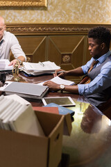 Aufkleber - Young African man and his mature colleague in formalwear working with business contracts and other documents in boardroom