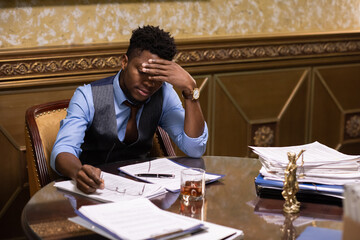 Aufkleber - Young African male lawyer in formalwear touching his head while looking through juridical documents by workplace