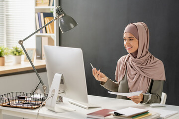 Aufkleber - Happy young Muslim woman talking to teacher on computer screen during online lesson in office environment