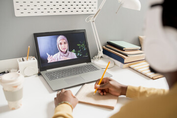 Aufkleber - Young Muslim woman on laptop screen teaching online learners while contemporary African student making notes
