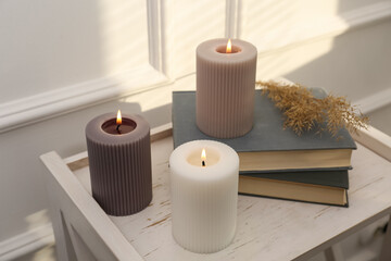 Wall Mural - Different burning candles and books on white table indoors