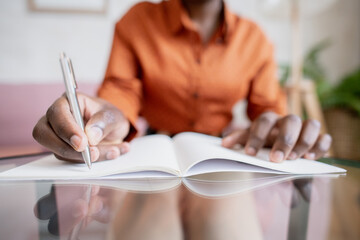 Aufkleber - Hand of young African female with pen over blank page of copybook writing down lecture notes while sitting by table