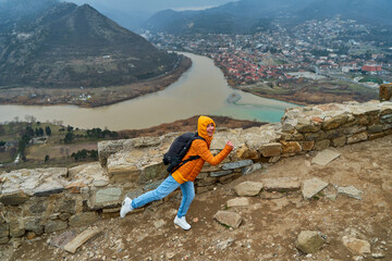 Young girl tourist rejoices posing against the backdrop of an amazing natural landscape. The confluence of two rivers in the city of Mtskheta in Georgia