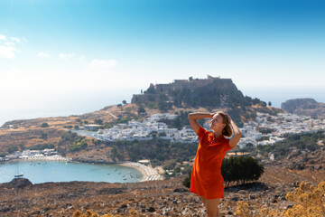 Wall Mural - A blonde woman looks at the panorama of Lindos on the island of Rhodes, Greece