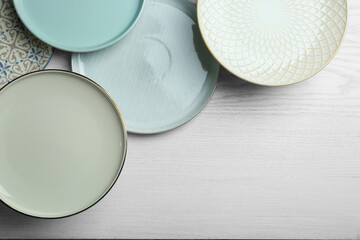 Wall Mural - Beautiful plates on white wooden table, flat lay. Space for text