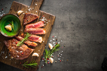 Poster - Beef steak. Grilled meat at wooden cutting board with spices. Top view image with copy space.