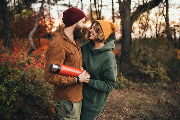 Wall Mural - Happy couple in love drinking tea from thermos in beautiful autumn forest.