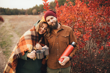 Wall Mural - Happy couple in love drinking tea from thermos in beautiful autumn forest.