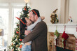 Dad hugging and kissing daughter in front of Christmas tree
