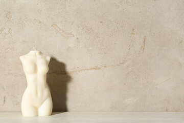 Wall Mural - Beautiful female body shaped candle on table near light wall, space for text