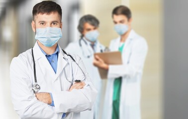 Wall Mural - Confident nurse in front of medical team looking at camera wearing a face mask during a covid-19