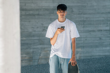 Poster - young teenager with mobile phone and skateboard on the street