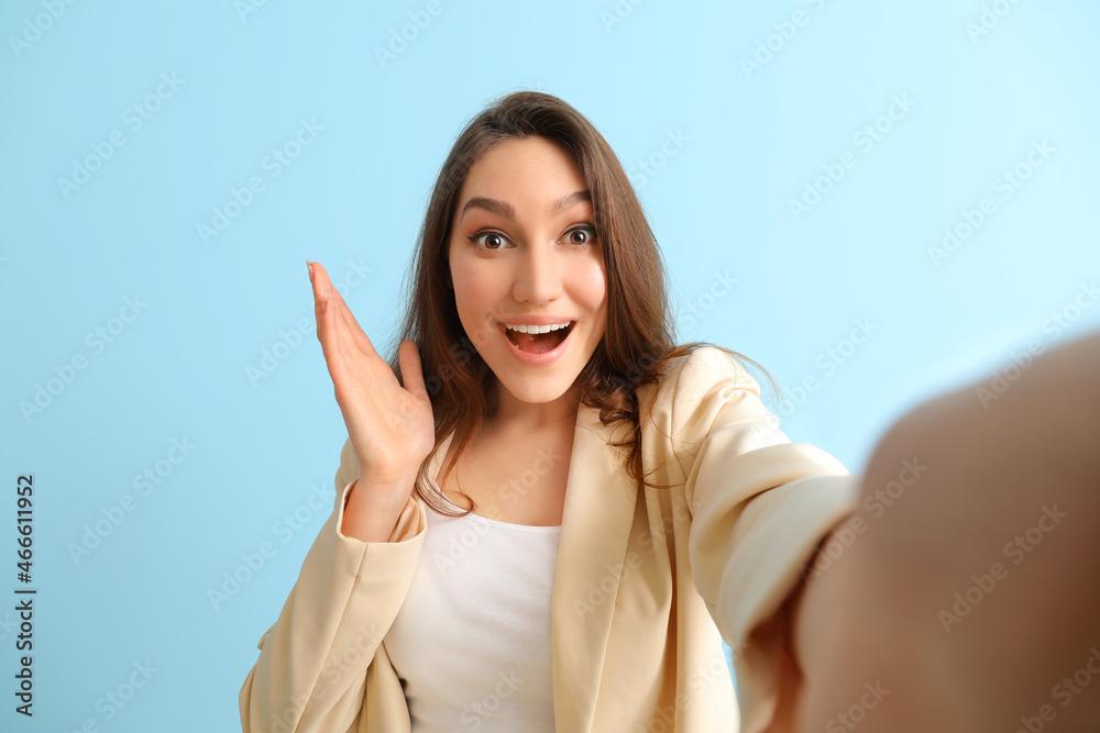 Beautiful surprised woman taking selfie on color background