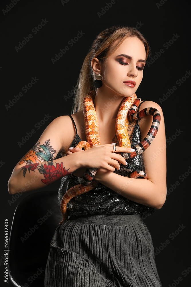 Sexy young woman with snakes on black background