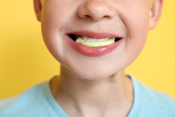 Poster - Little boy chewing gum on yellow background, closeup