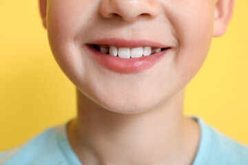 Canvas Print - Little boy with healthy smile on yellow background, closeup