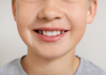 Wall Mural - Little boy with healthy smile on light background, closeup