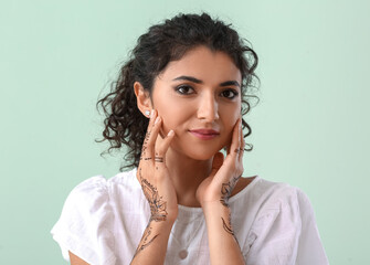 Wall Mural - Beautiful Indian woman with henna tattoo on color background